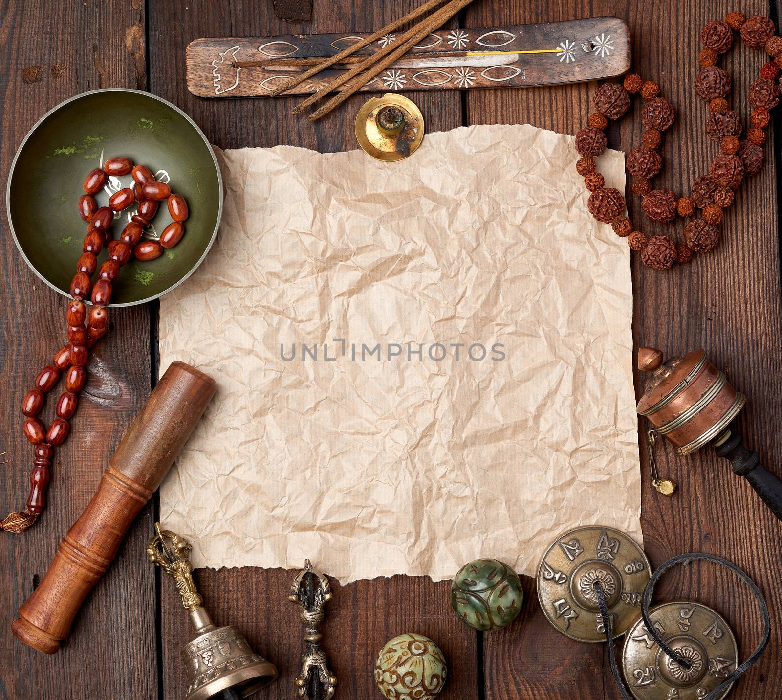 tibetan religious objects for meditation and alternative medicine, empty brown sheet of paper on a brown  wooden background, top view