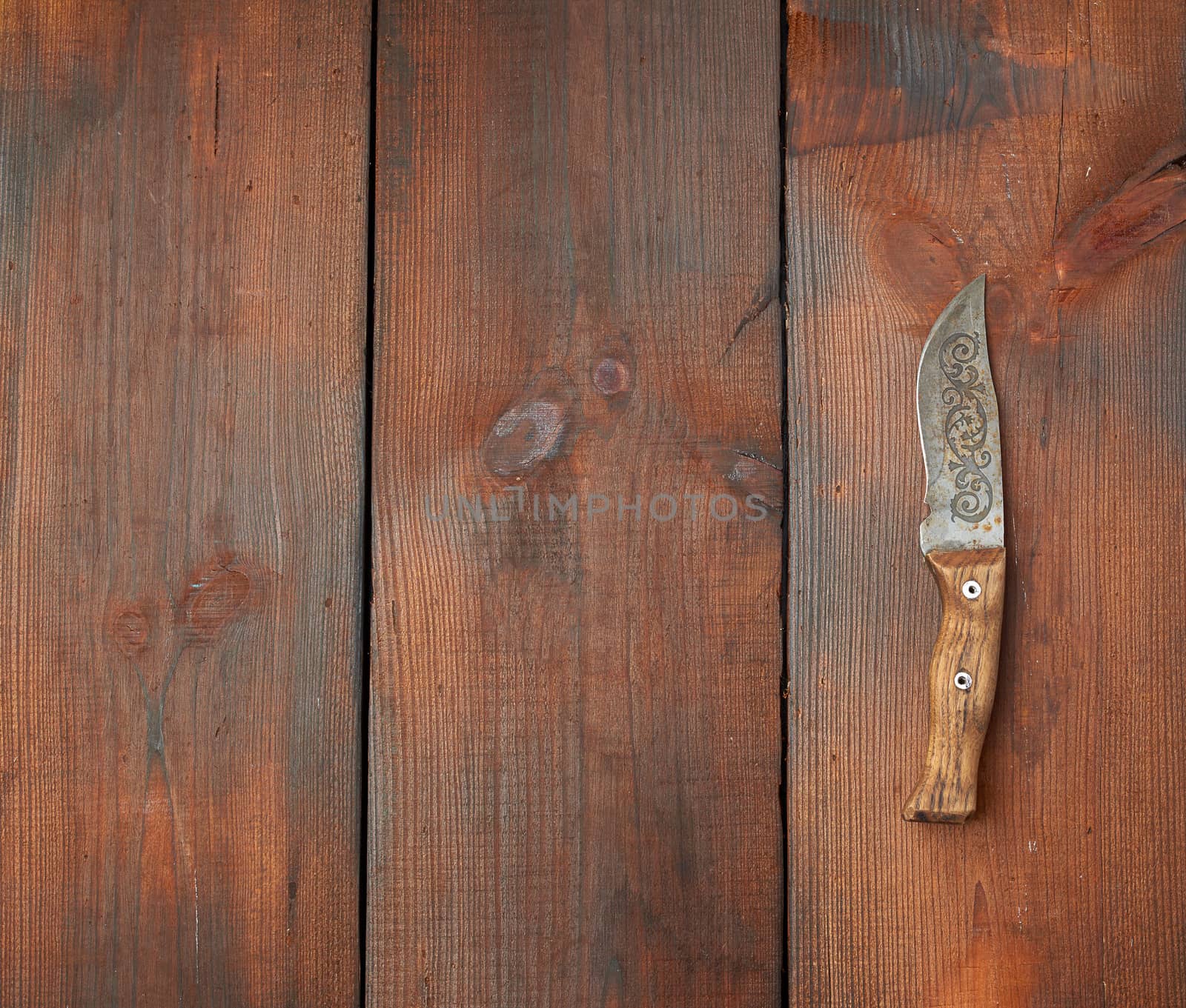 vintage steel sharp knife on a brown wooden table made of boards, top view, place for text
