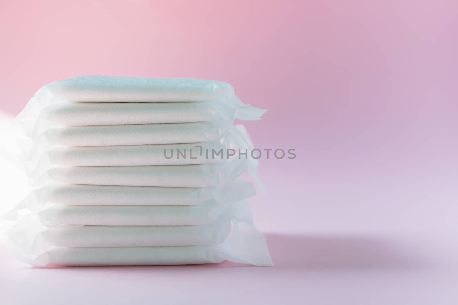 Feminine sanitary napkin, an absorbent item worn by a woman while menstruating, on pink background for hygiene and health concept
