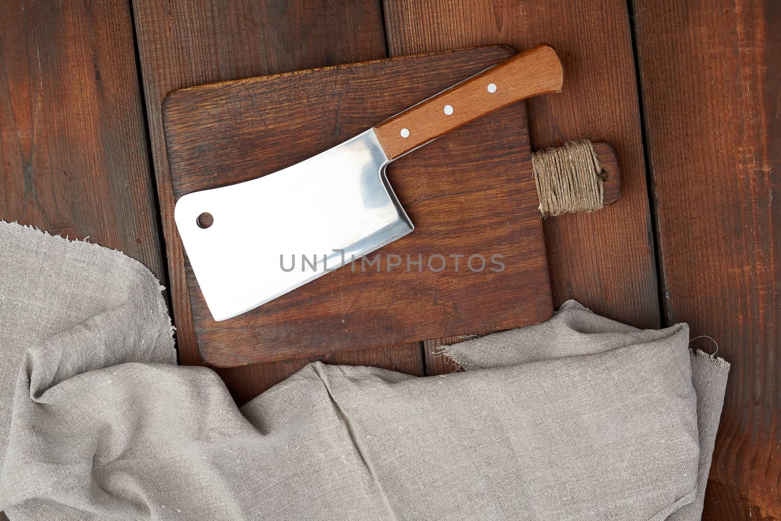 large steel sharp meat knife lies on a rectangular wooden brown board, top view