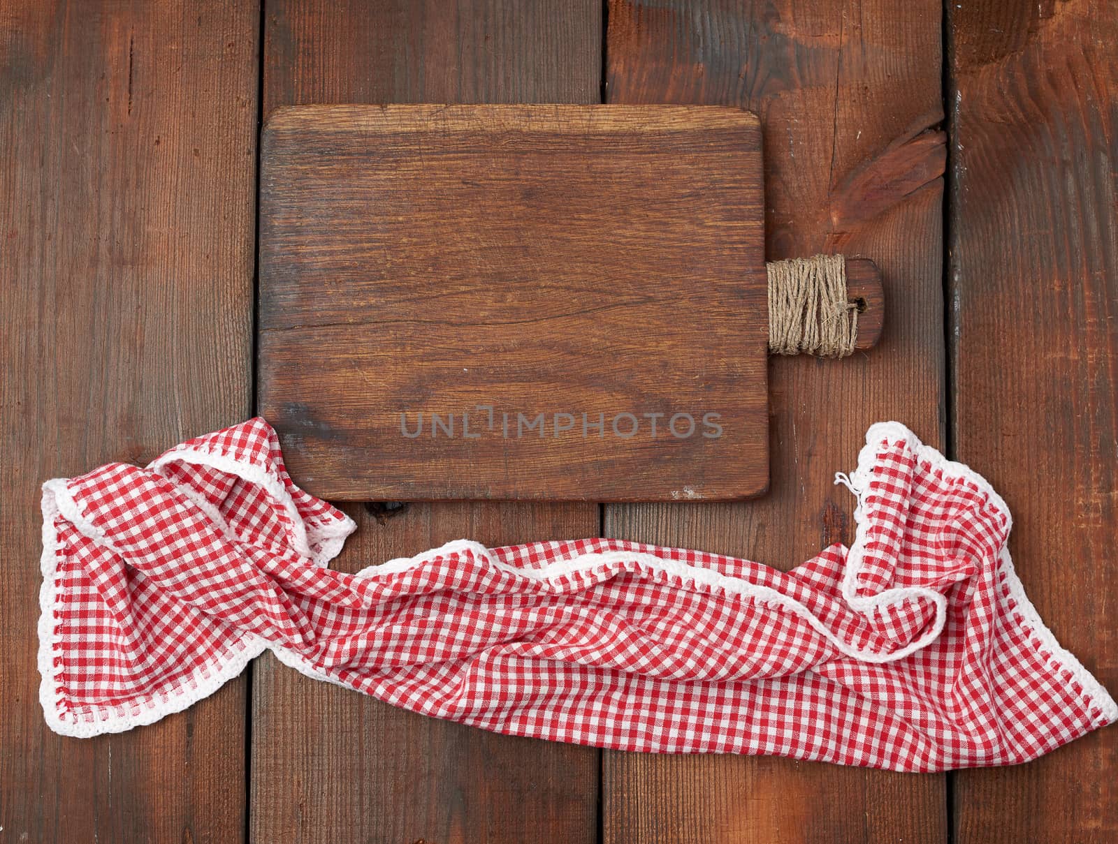 empty very old rectangular cutting wooden board and red kitchen towel on a wooden surface
