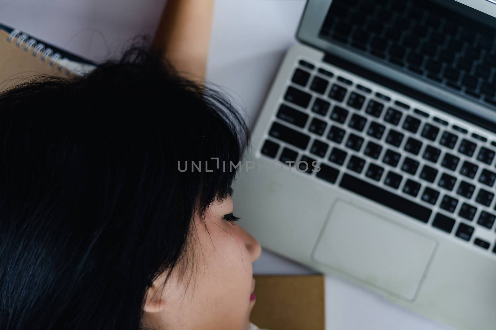 Asian woman working hard, getting tired and sleeping over laptop on office desk for career and employment concept