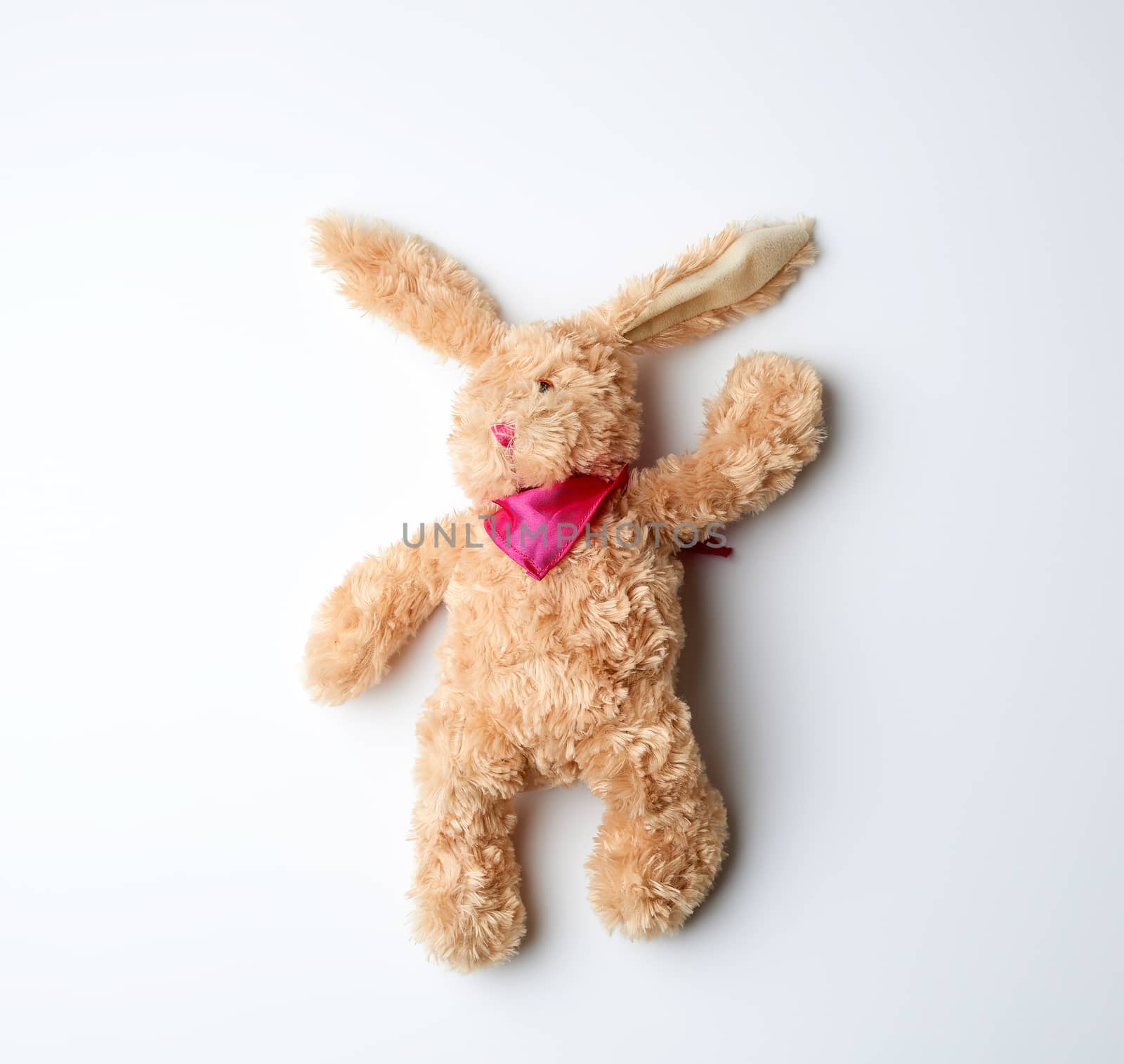 toy brown plush hare lies on a white background, top view