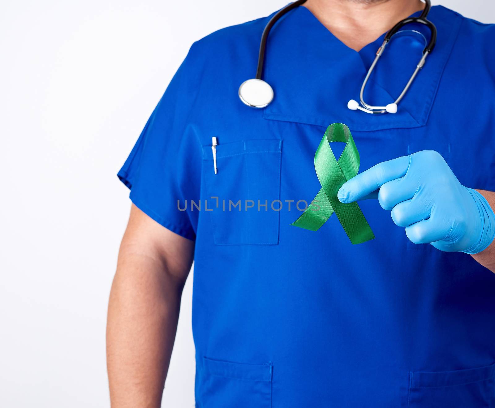 doctor in blue uniform and latex gloves holds a green ribbon as a symbol of early research and disease control, symbol of Lyme disease, kidney transplantation and organ donation