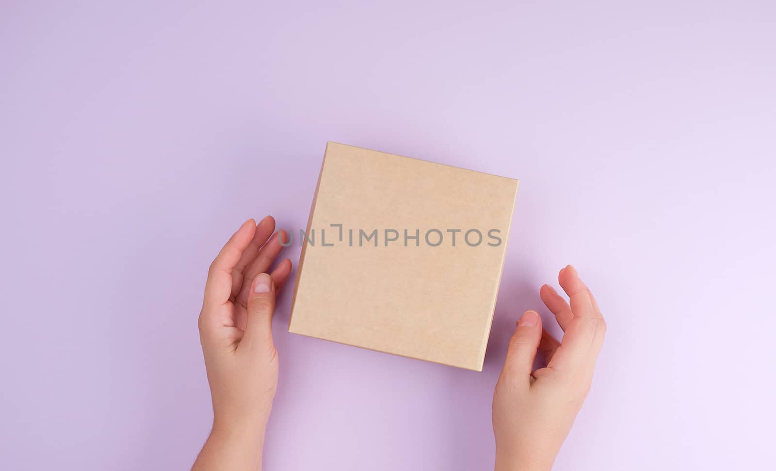 girl hold a brown square box on a purple background, top view, concept of giving gifts