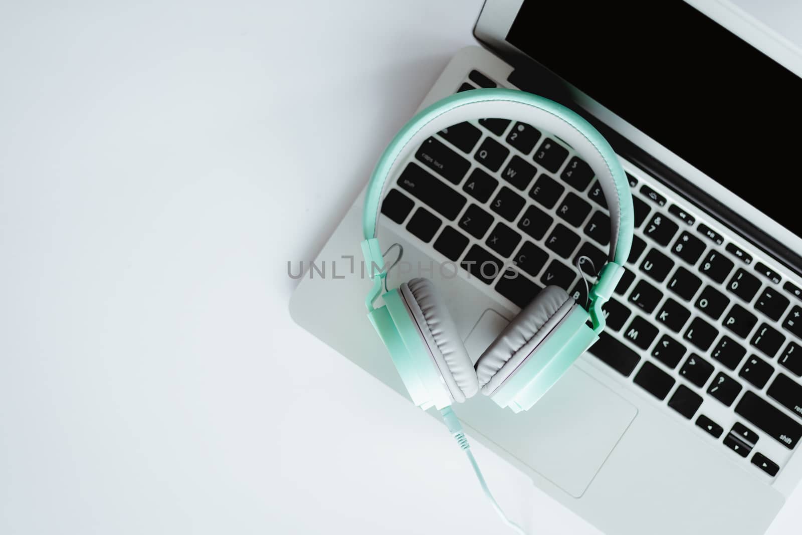 Top view of headphones with computer laptop on white office desk for entertainment and leisure online concept