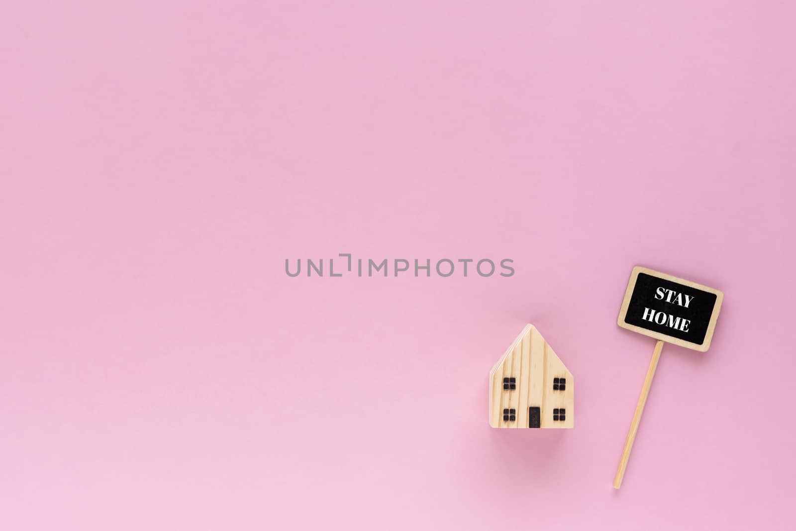Wooden house model with stay home text on pink background for self-quarantine and staying home in coronavirus or Covid-19 situation concept