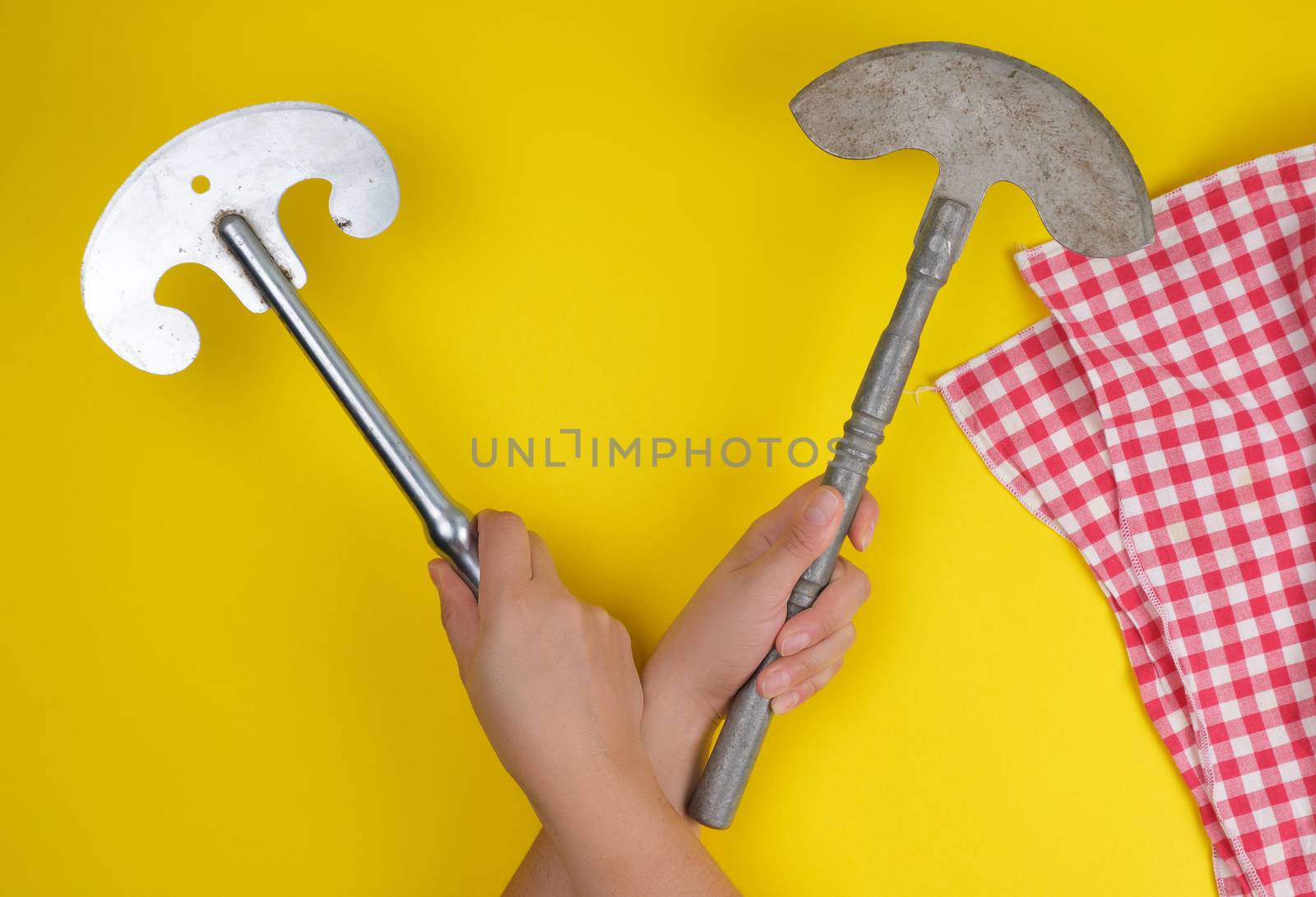 two hands holding vintage sharp kitchen knives for meat and vegetables, yellow background