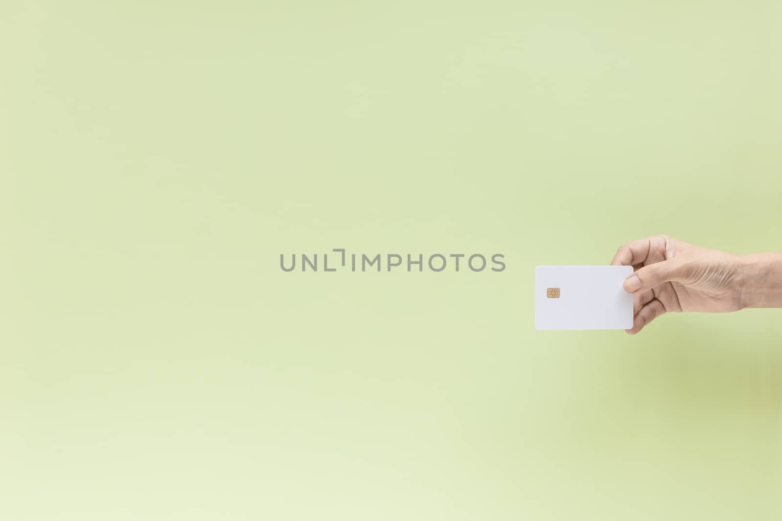 Hand holding blank credit chip card on green background with copy space for business and finance concept