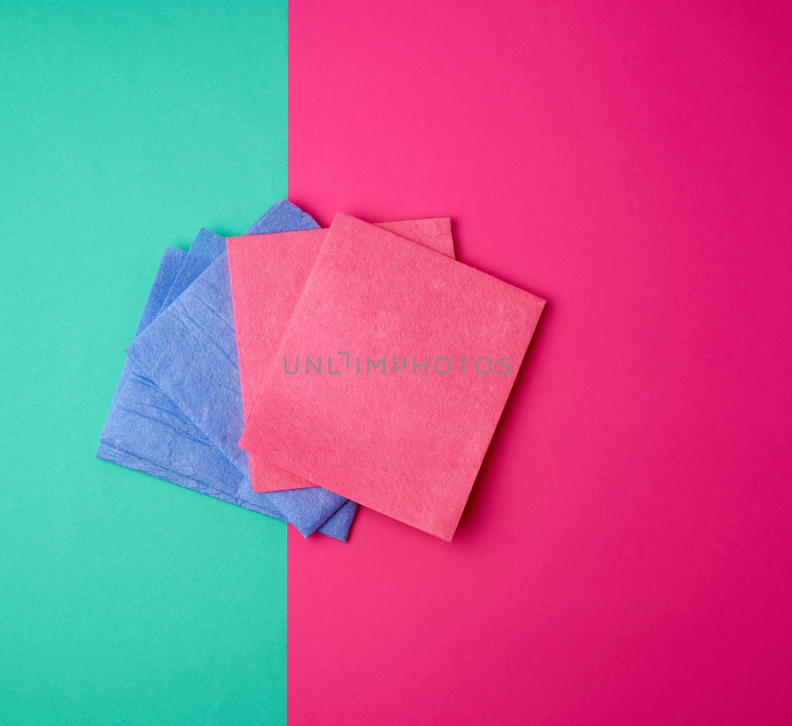 multi-colored square dishwashing sponges on a pink green background, top view, flat lay