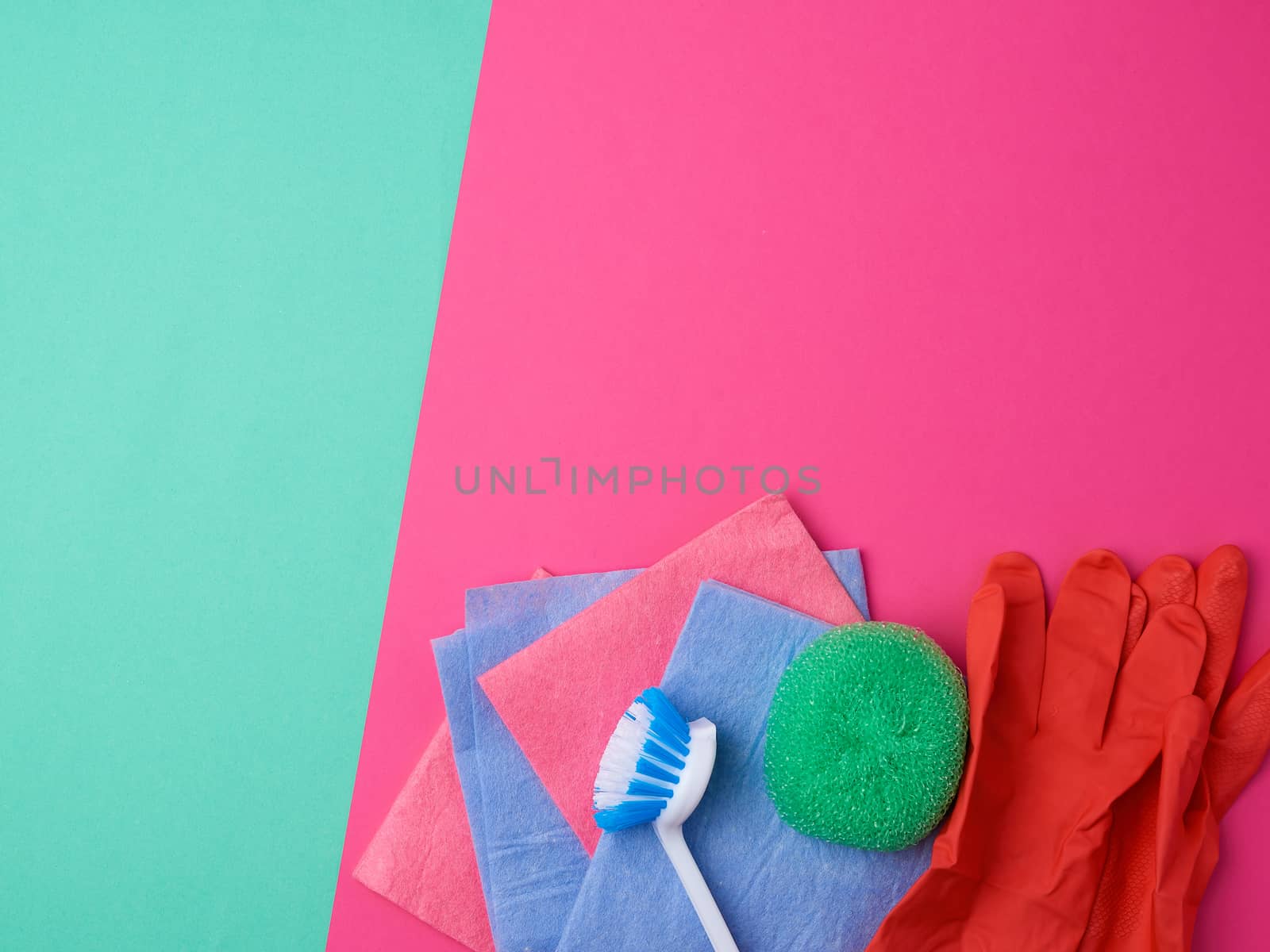items for home cleaning: red rubber gloves, brush, multi-colored sponges for dusting on a pink green background, top view, flat lay