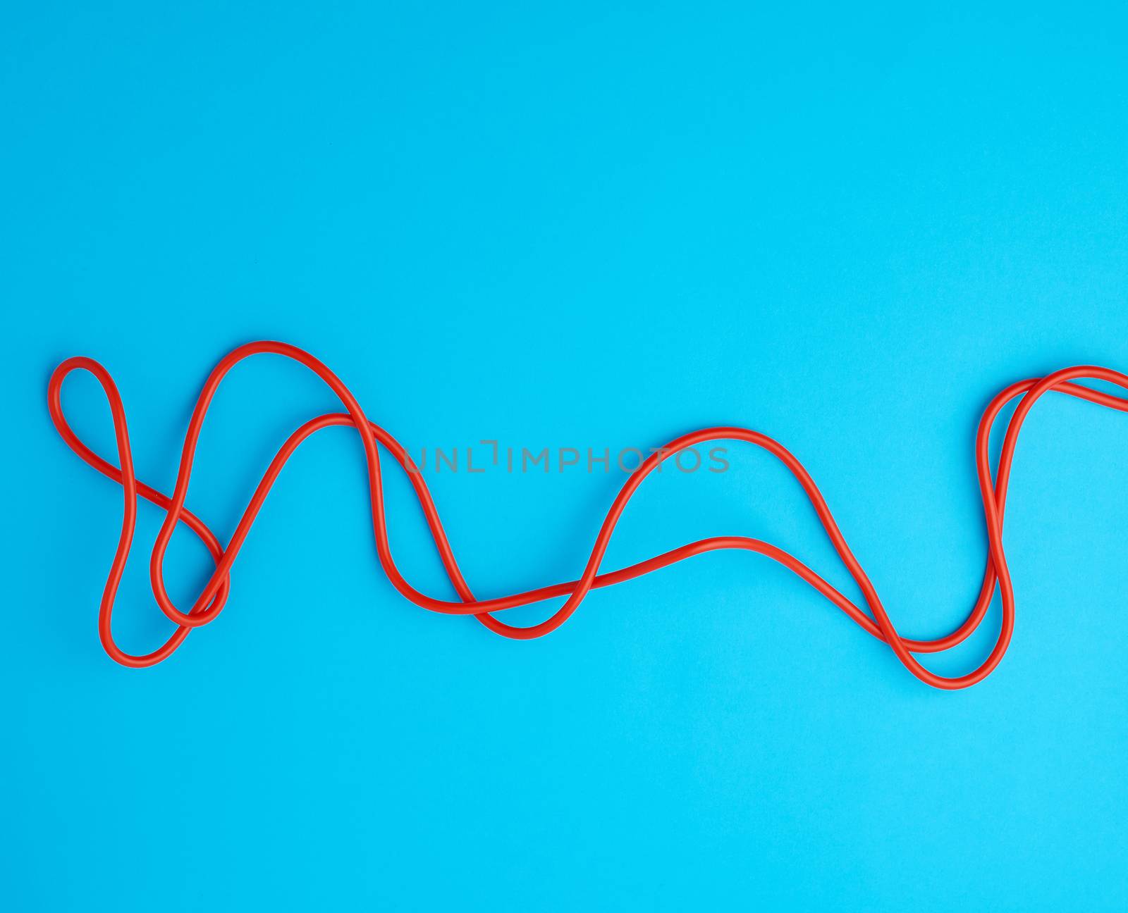 fragment of a red jump rope for sports on a blue background, two lines