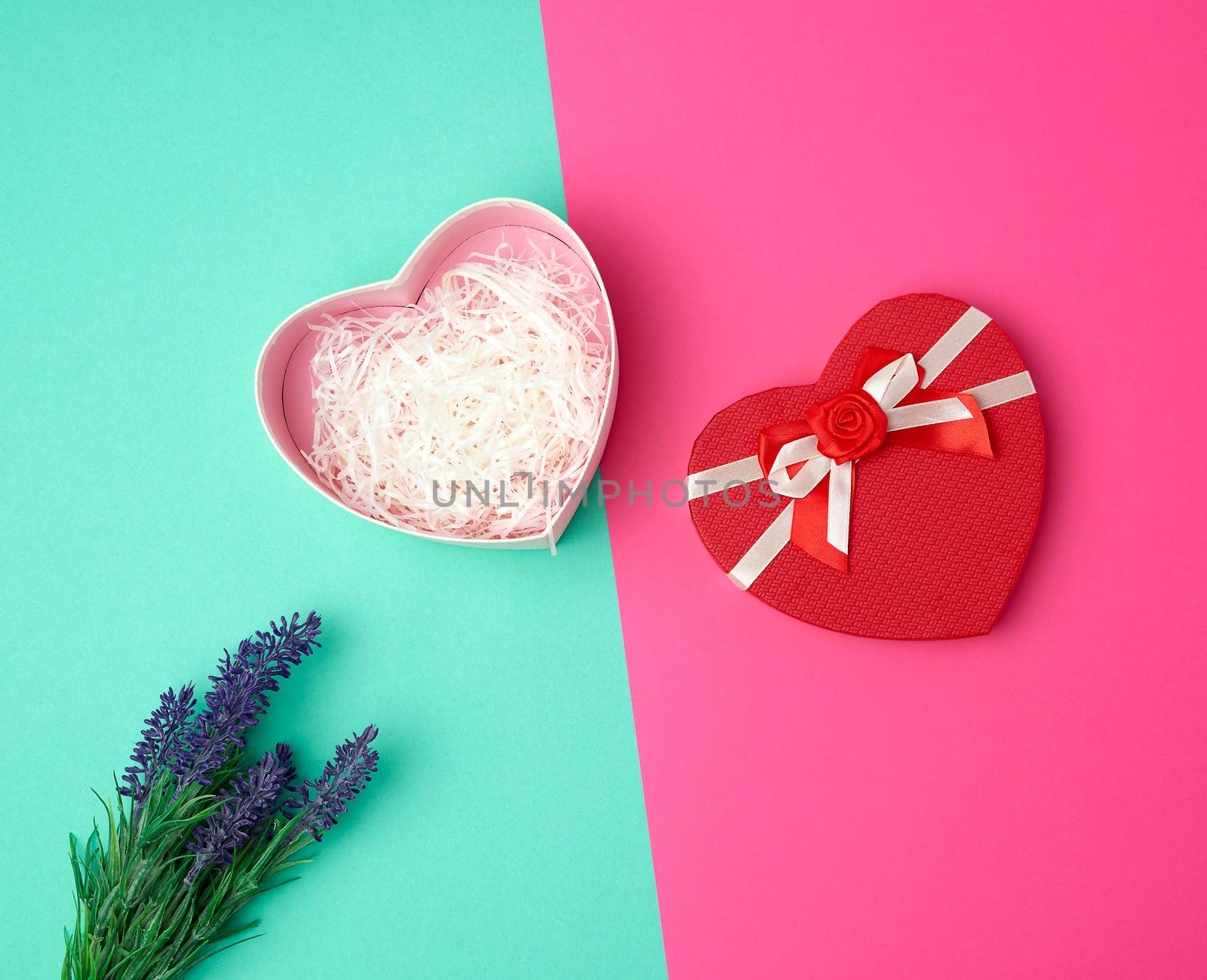 open red heart-shaped gift box with a bow on a pink green background, top view, festive backdrop