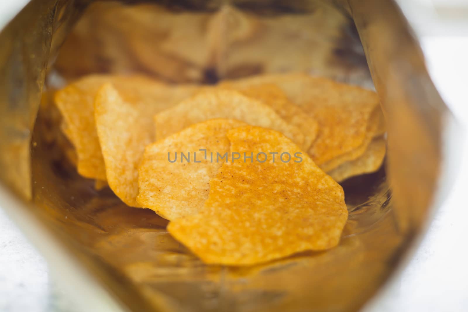 Close up of baked potato chips in opened snack bag for food concept