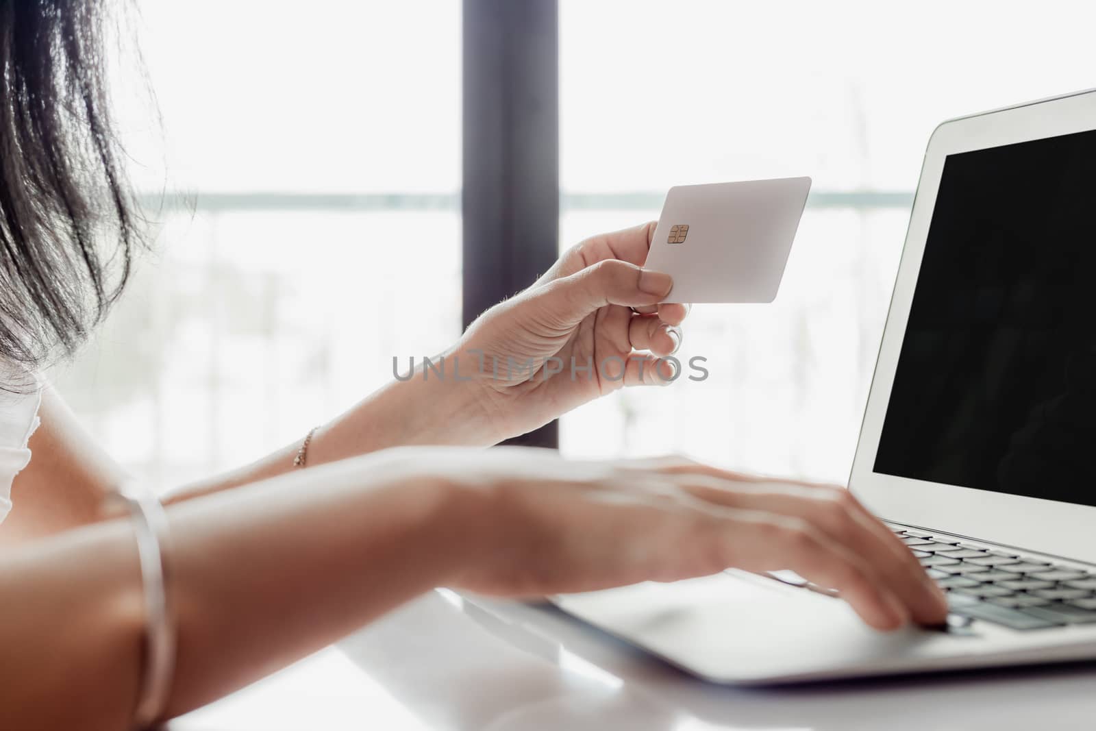 Woman's hand holding a credit card and using computer for online shopping and payment concept