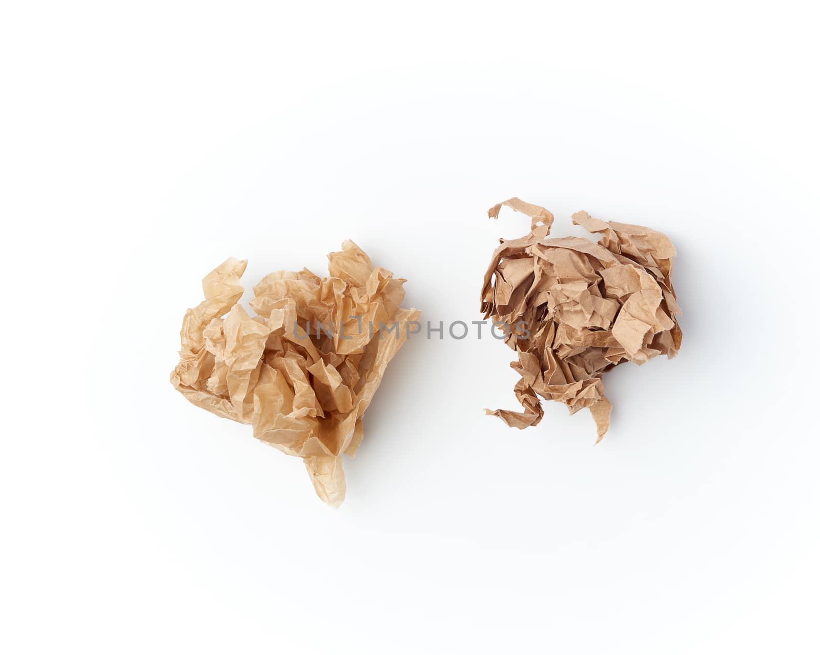 two crumpled sheets of brown paper on a white background, close up, top view