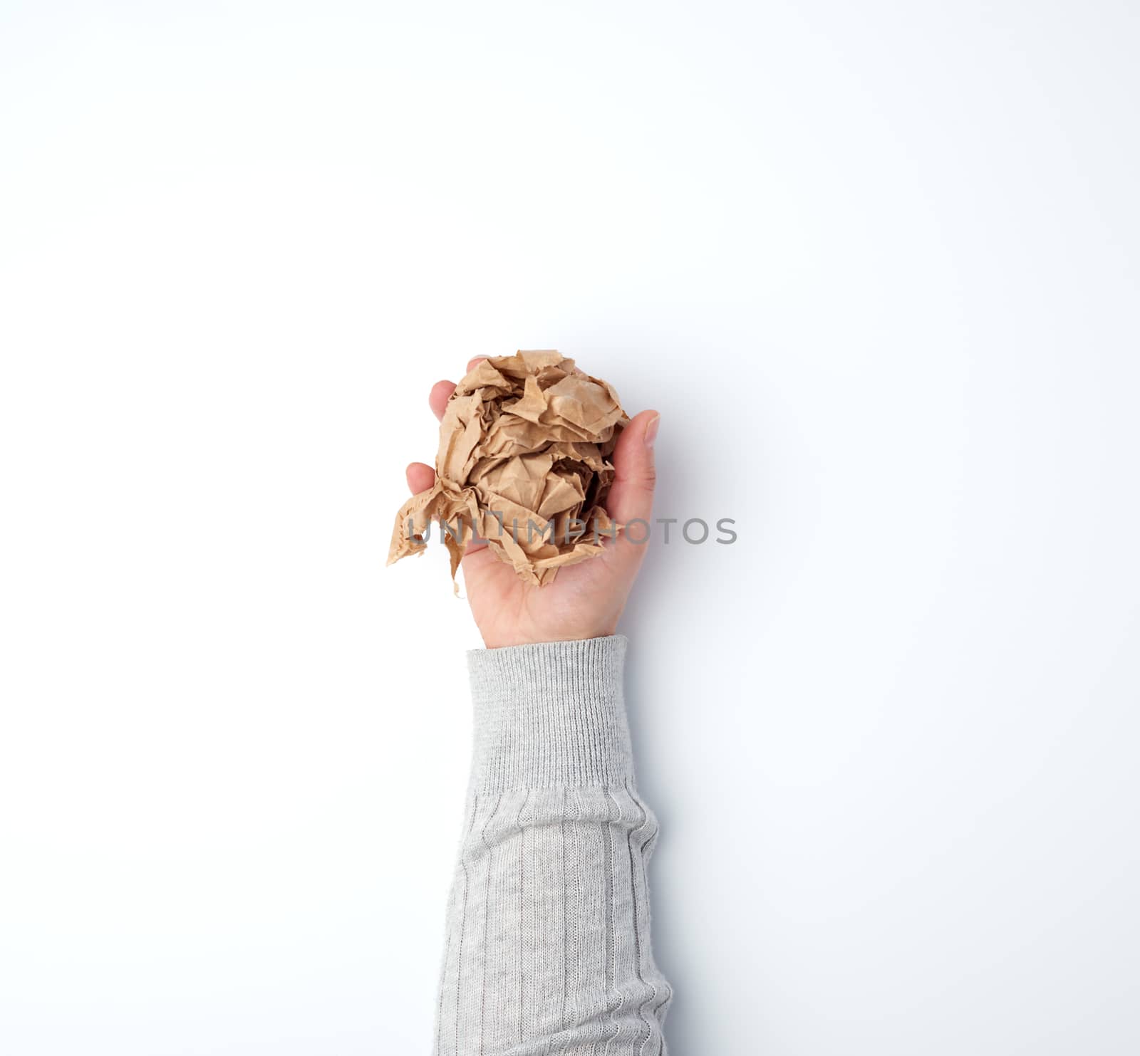 hand holds a crumpled sheet of brown paper on a white background, top view