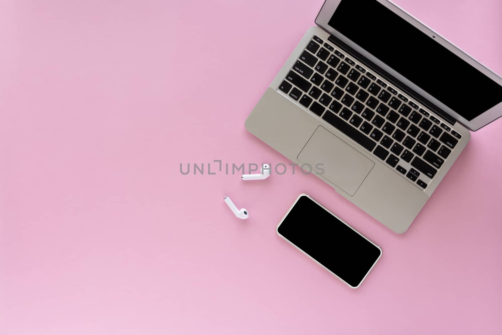 Computer laptop and smartphone with wireless headphones on pink background with copy space for media technology and modern lifestyle concept