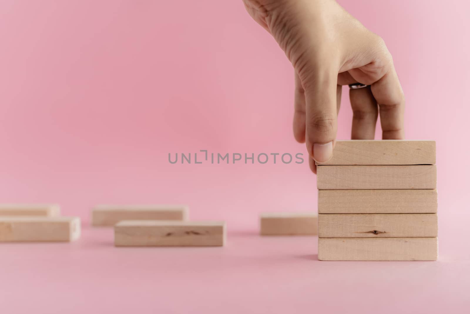 Hand putting the wooden toy on pink background for leisure activities concept