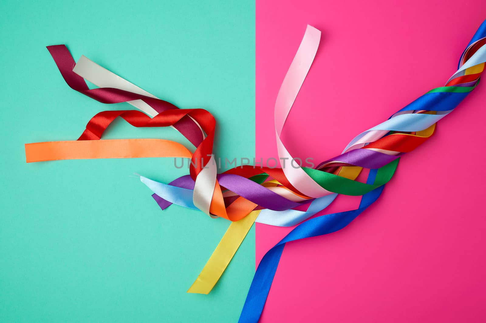 many silk multi-colored ribbons on a colored background, top view