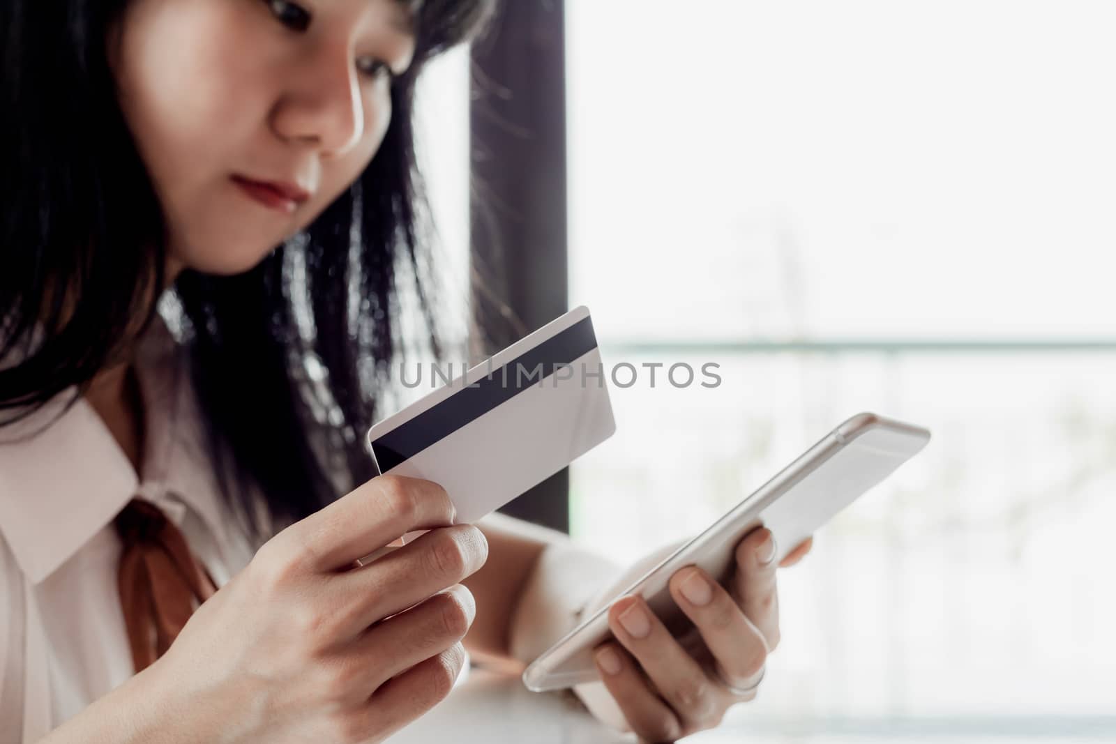 Asian woman holding a credit card and using smartphone for online shopping and payment concept