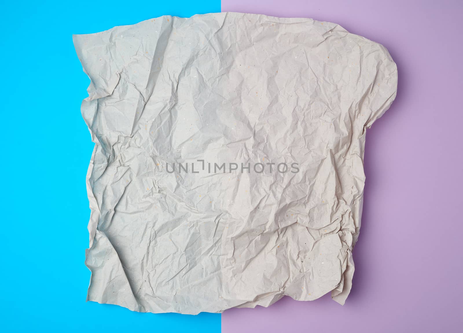 crumpled piece of gray paper on a colored background, top view, place for text
