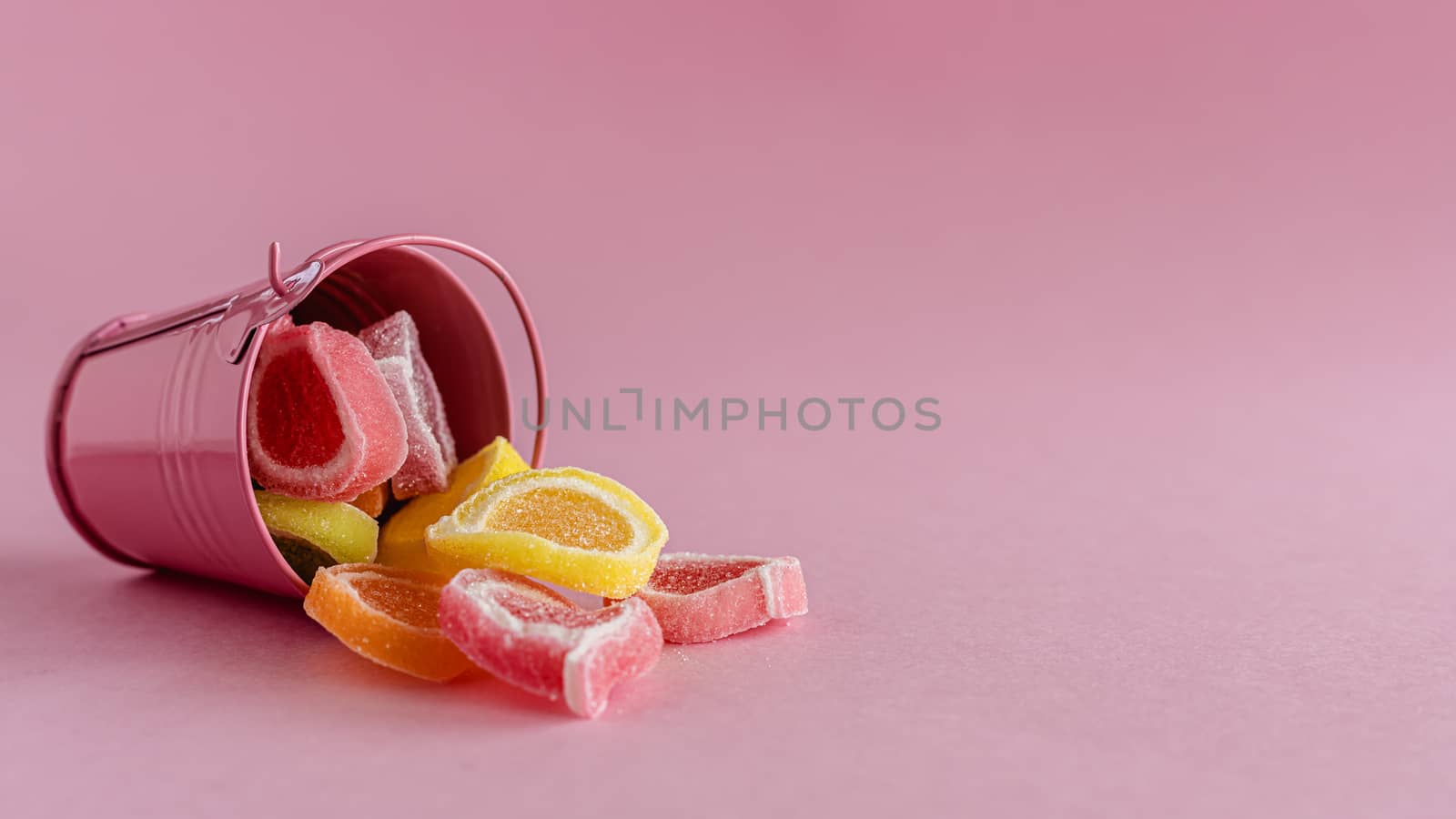 Colourful fruit Jelly candy in a pink bucket against pink background for food and snack concept