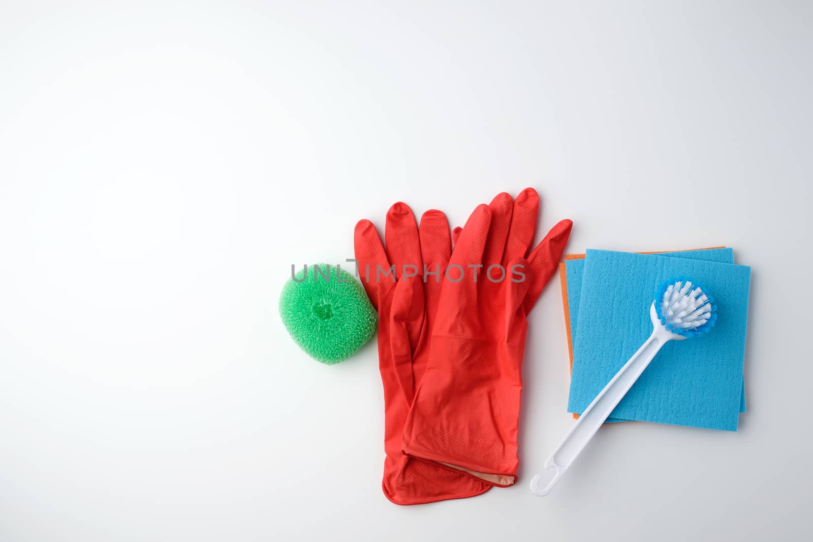 items for home cleaning: red rubber gloves, brush, multi-colored sponges for dusting on a white background, top view, flat lay