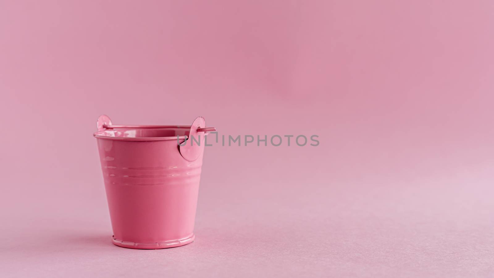 Mini colored tin pail or bucket on pink background with copy space for household items concept