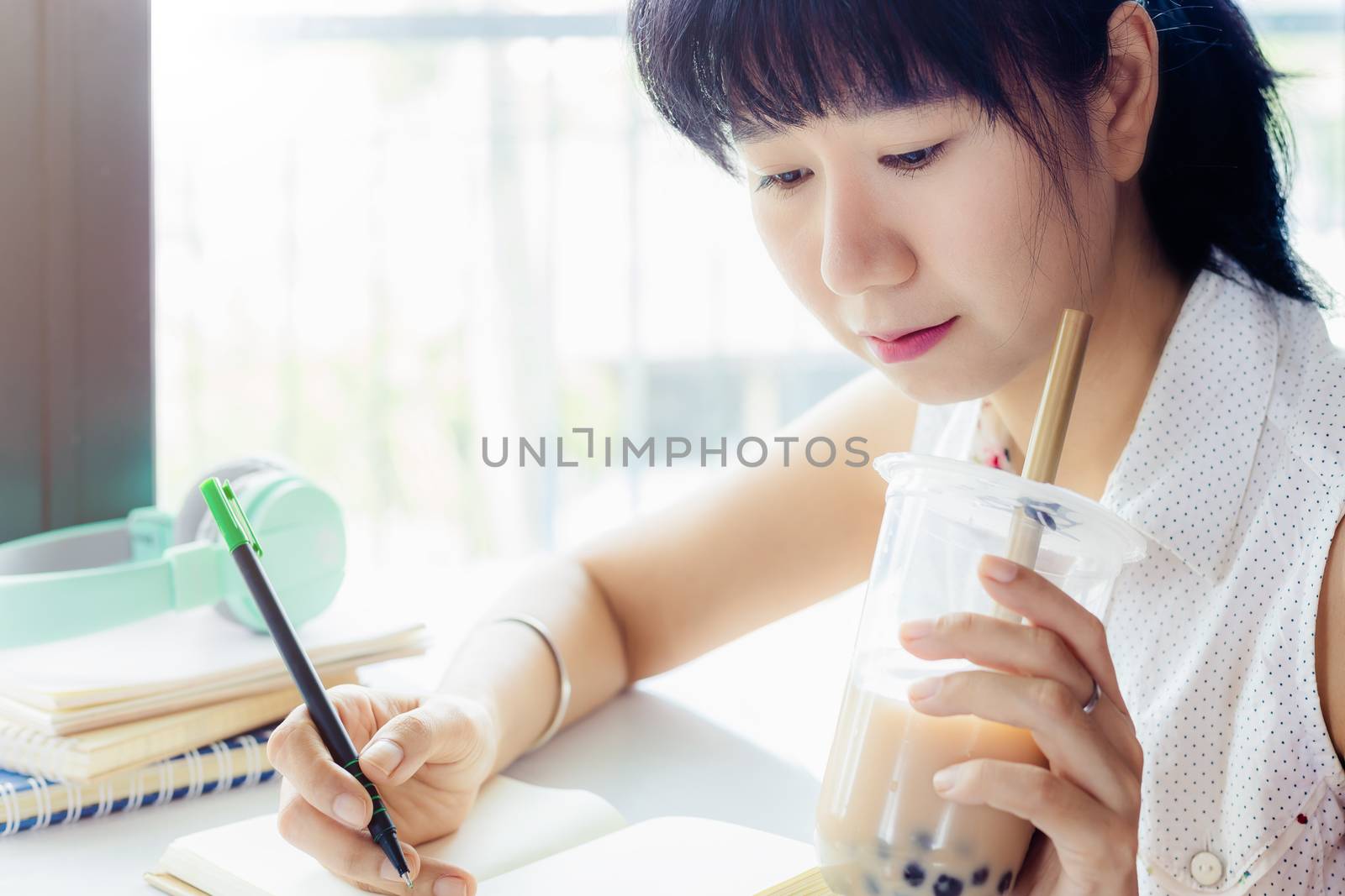 Asian woman working and drinking bubble tea with blurred background for stay at home concept