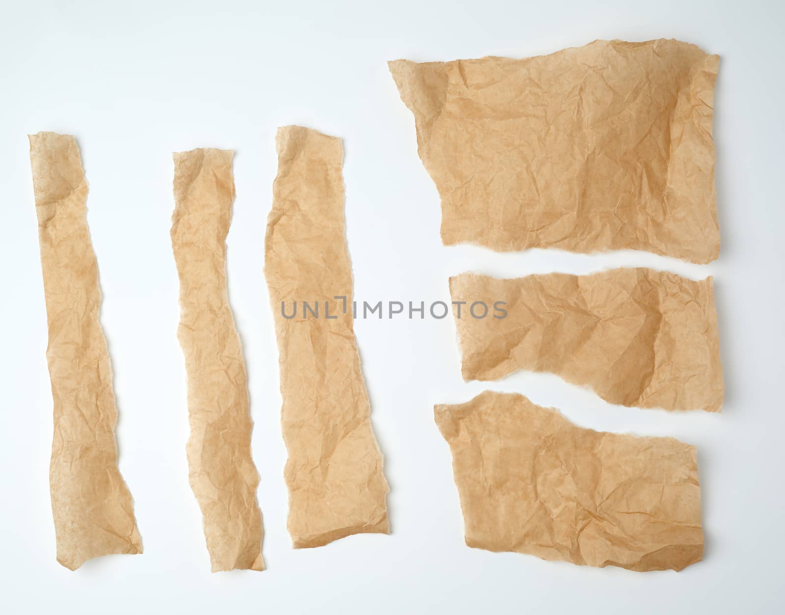 torn brown pieces of parchment paper on a white background, flat lay