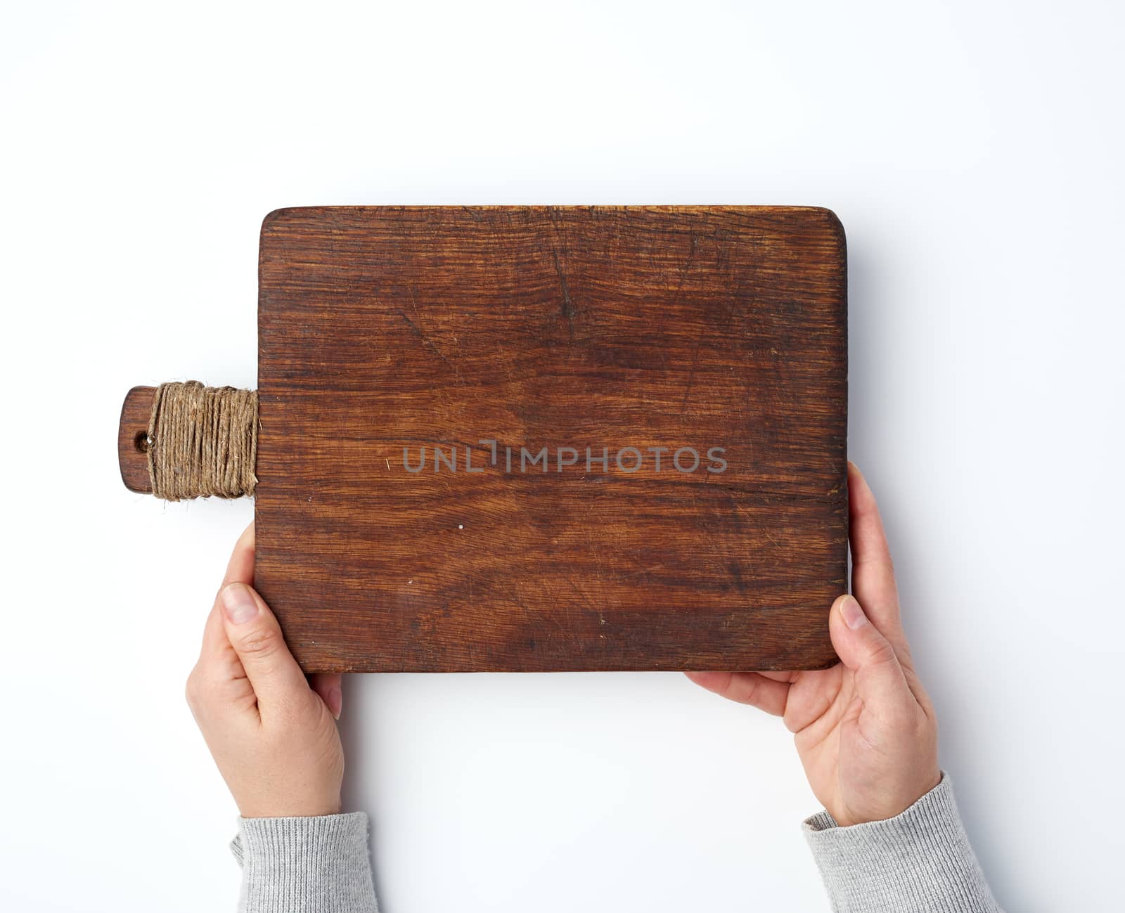 female hands holding an old empty wooden rectangular cutting board, top view, white background