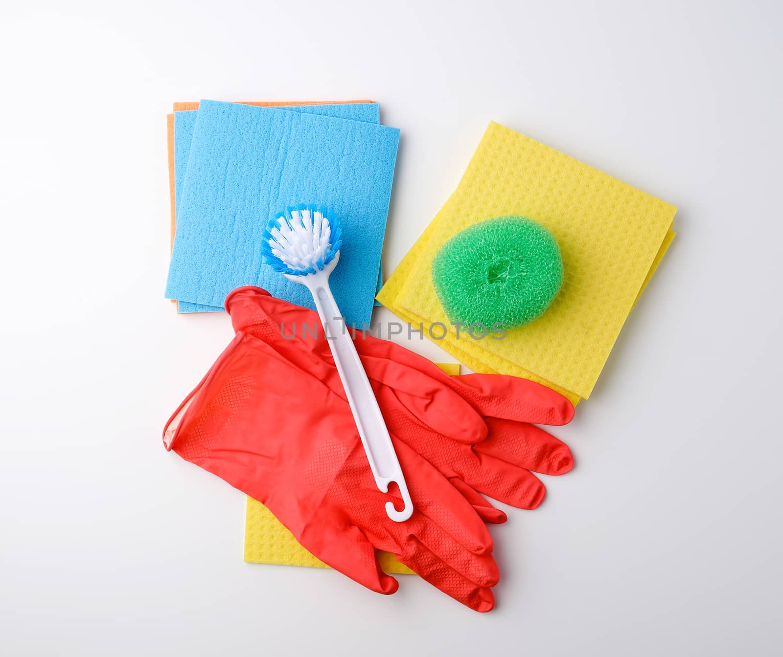 items for home cleaning: red rubber gloves, brush, multi-colored sponges for dusting on a white background, top view, flat lay