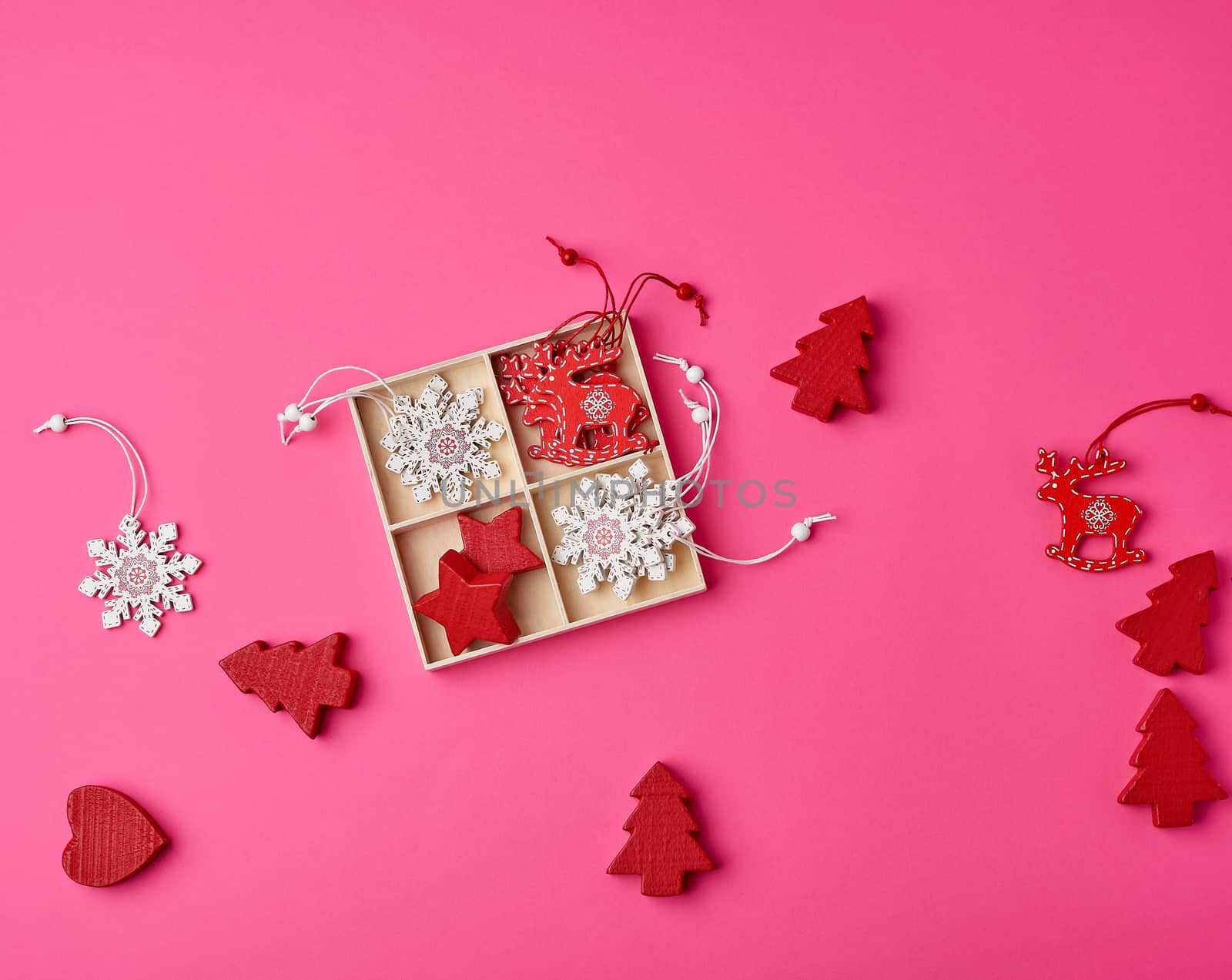 wooden carved Christmas decorations for the holiday tree on a pink background, top view