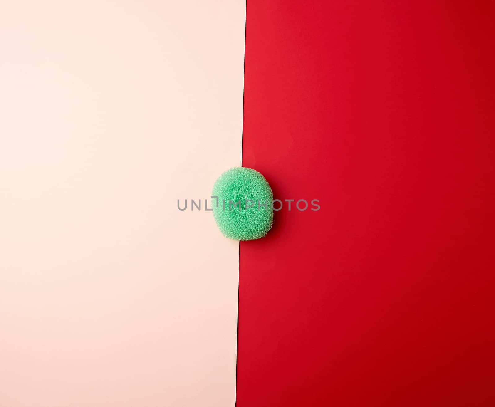 green round plastic scraper for washing dishes on a colored background, top view, flat lay, minimalism