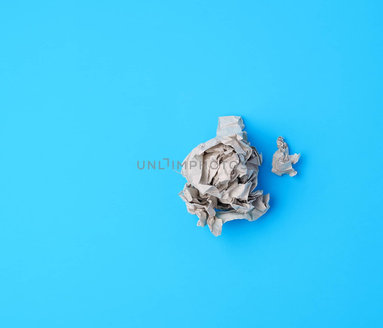 ball of crumpled gray paper on a blue background, top view
