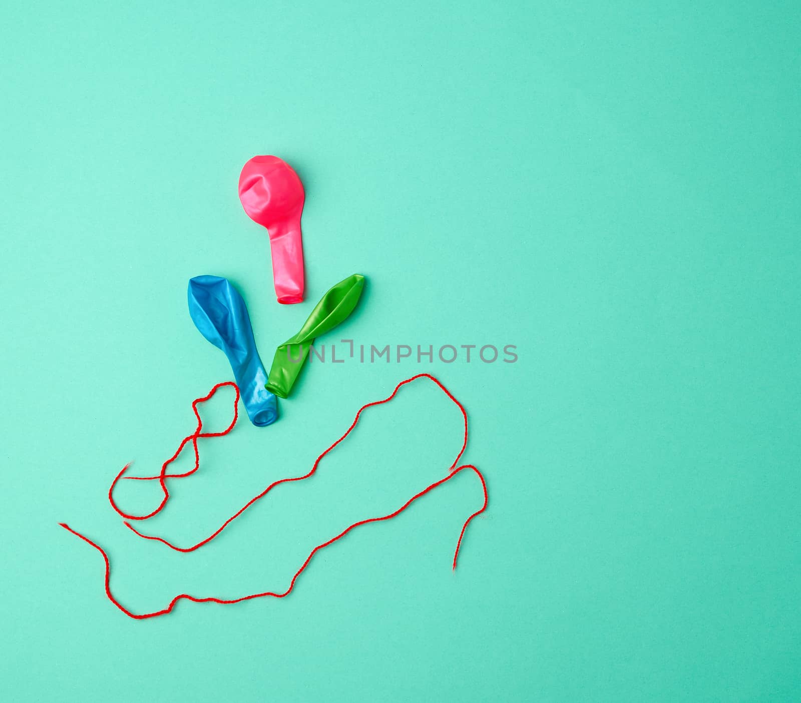 deflated rubber balls and red rope on a green background, copy space
