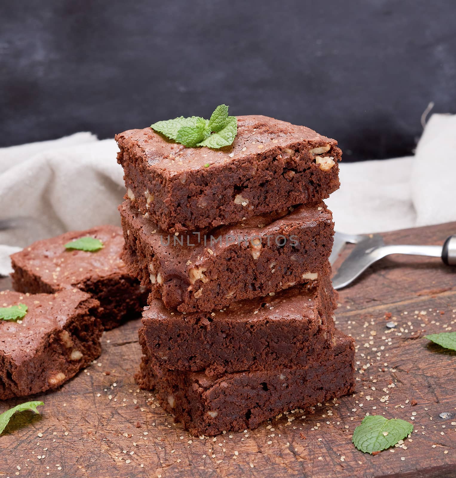 stack of baked square pieces of chocolate brownie pie with walnuts, close up