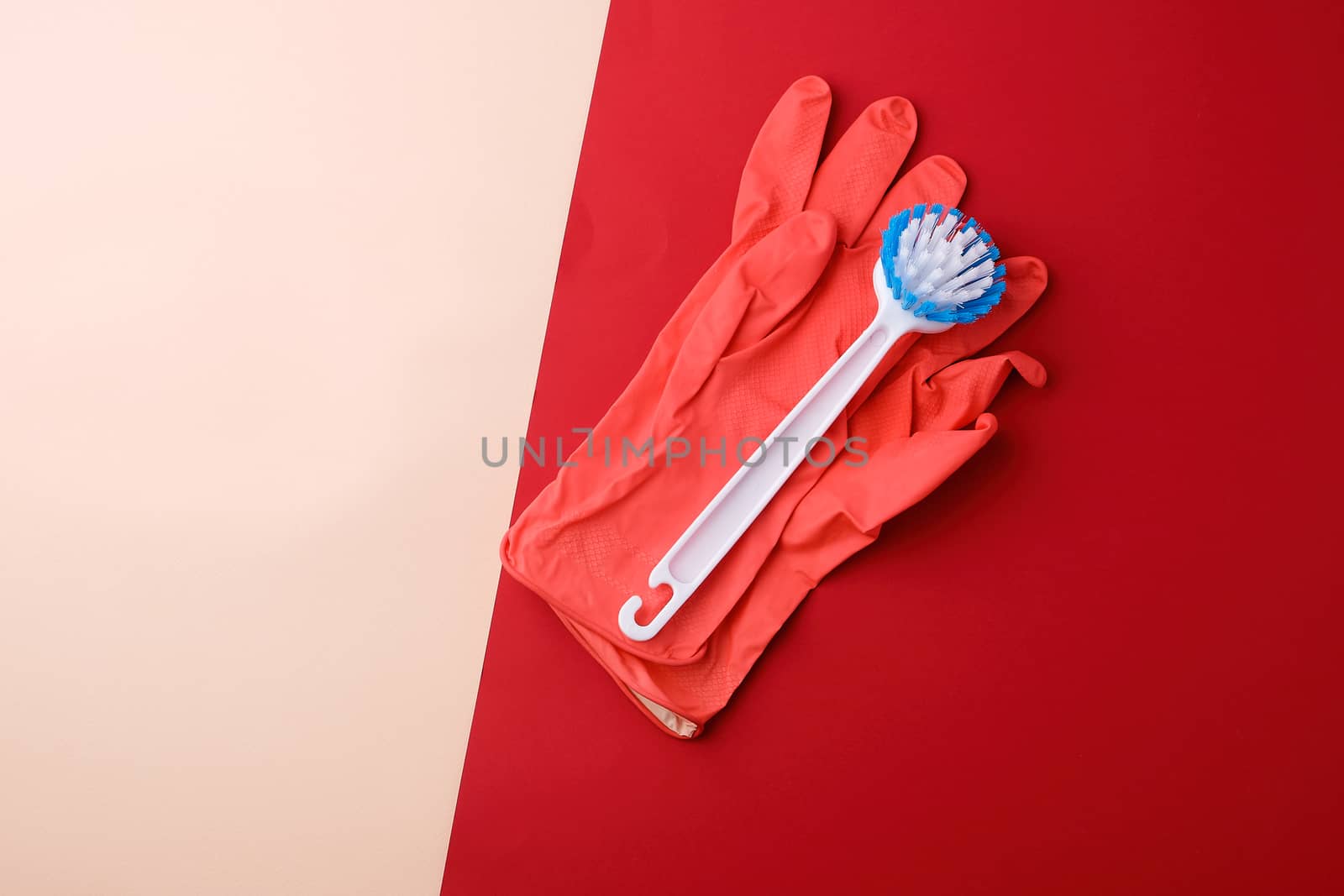 white brush and pink rubber gloves for cleaning the house on a red-beige background, top view, flat lay