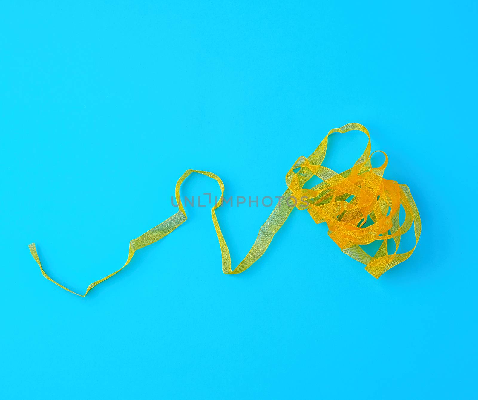 curled yellow satin ribbon on blue background, festive backdrop