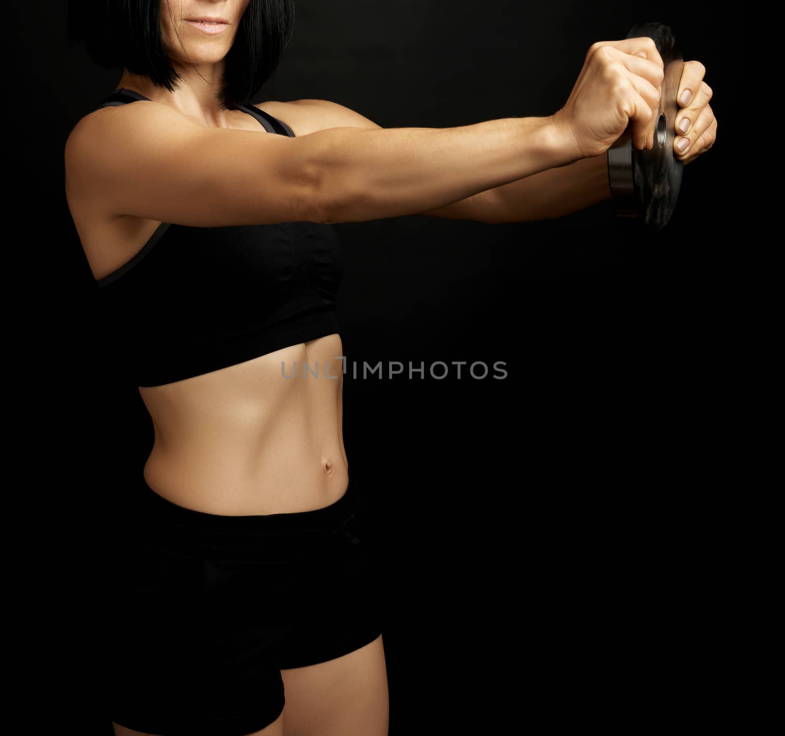  woman with black hair and a sports figure holds a steel circle for sports, low key