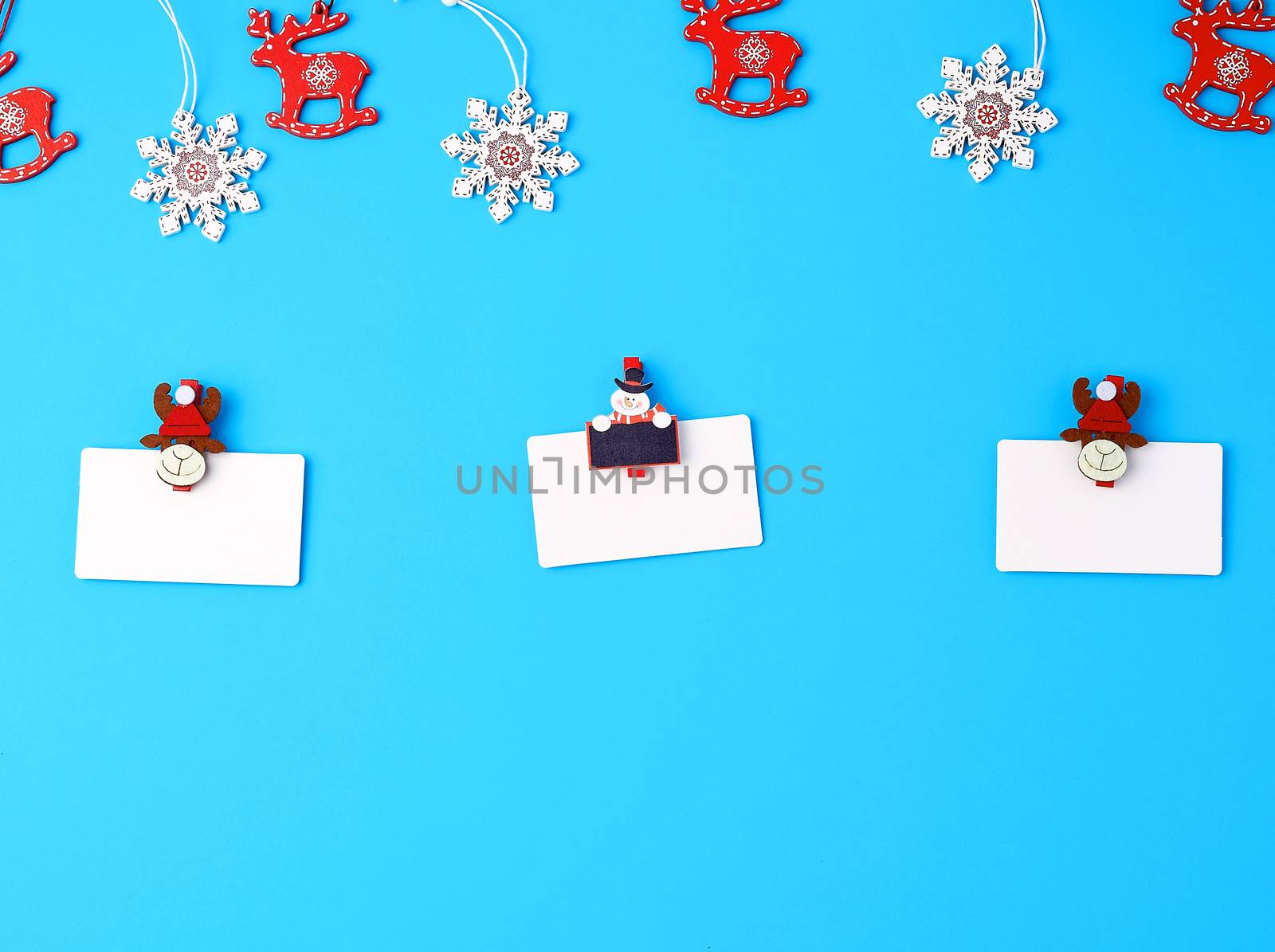 empty white paper business cards and holiday clothespins on a blue background, top view