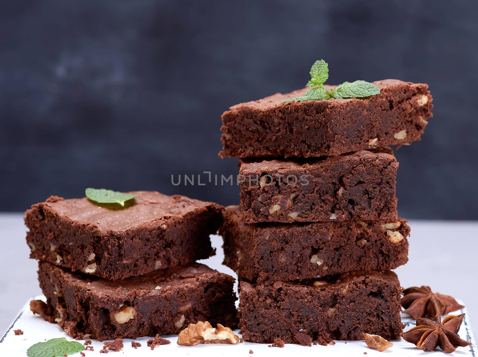 stack of baked square pieces of chocolate brownie pie with walnuts, close up