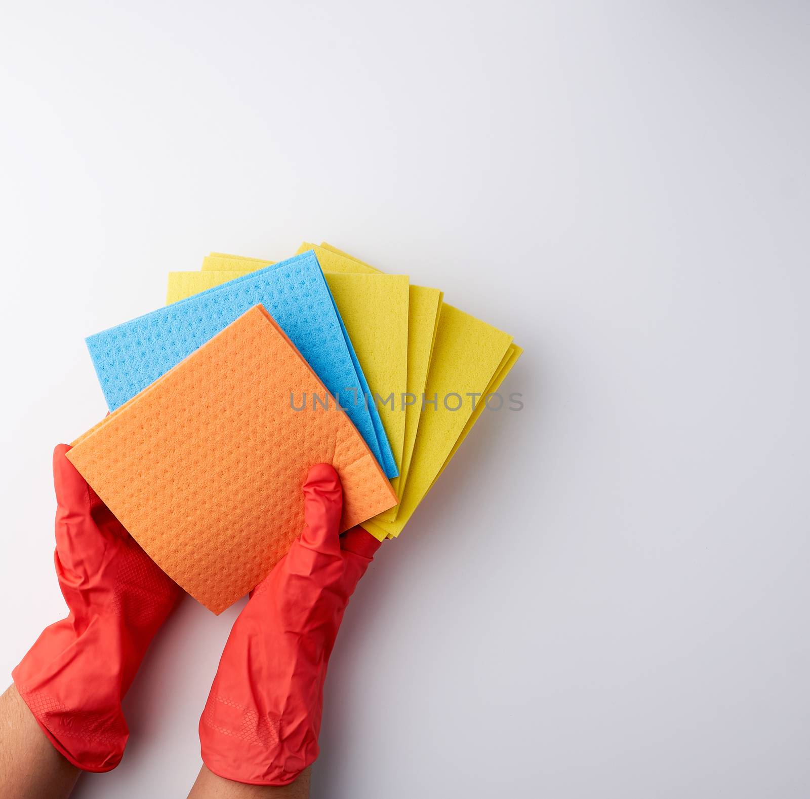 multi-colored square absorbent sponges in their hands wearing red rubber gloves, white background, top view, place for text