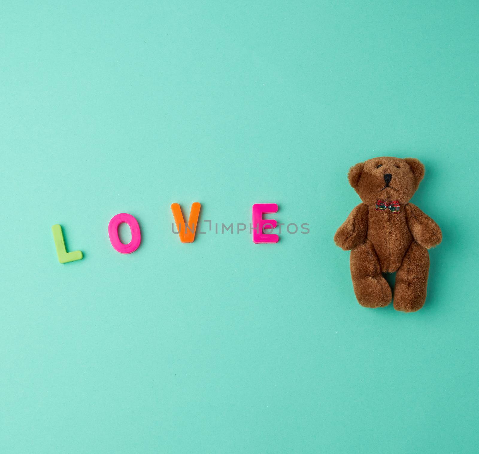 little cute brown teddy bear and the inscription love made of plastic letters
