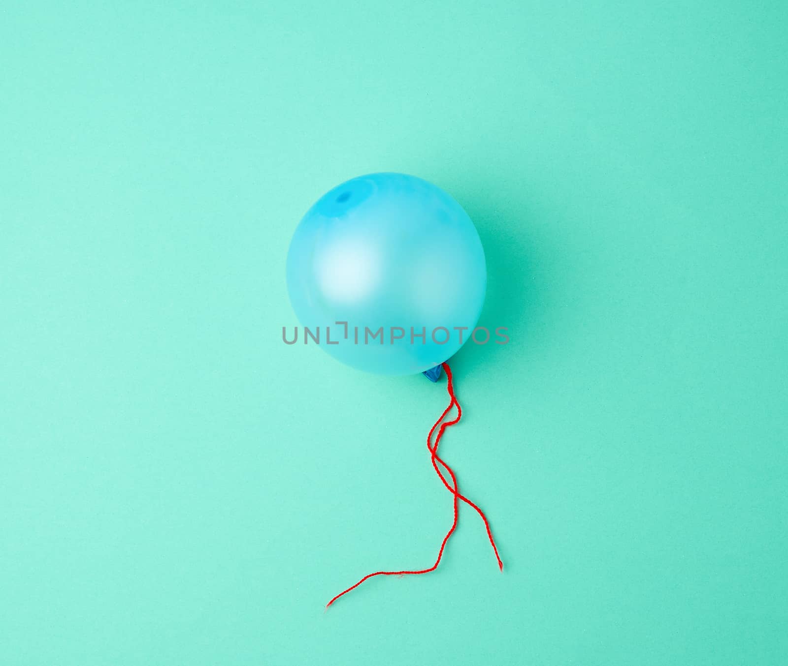 inflated blue rubber balloon on a green background, blue rope