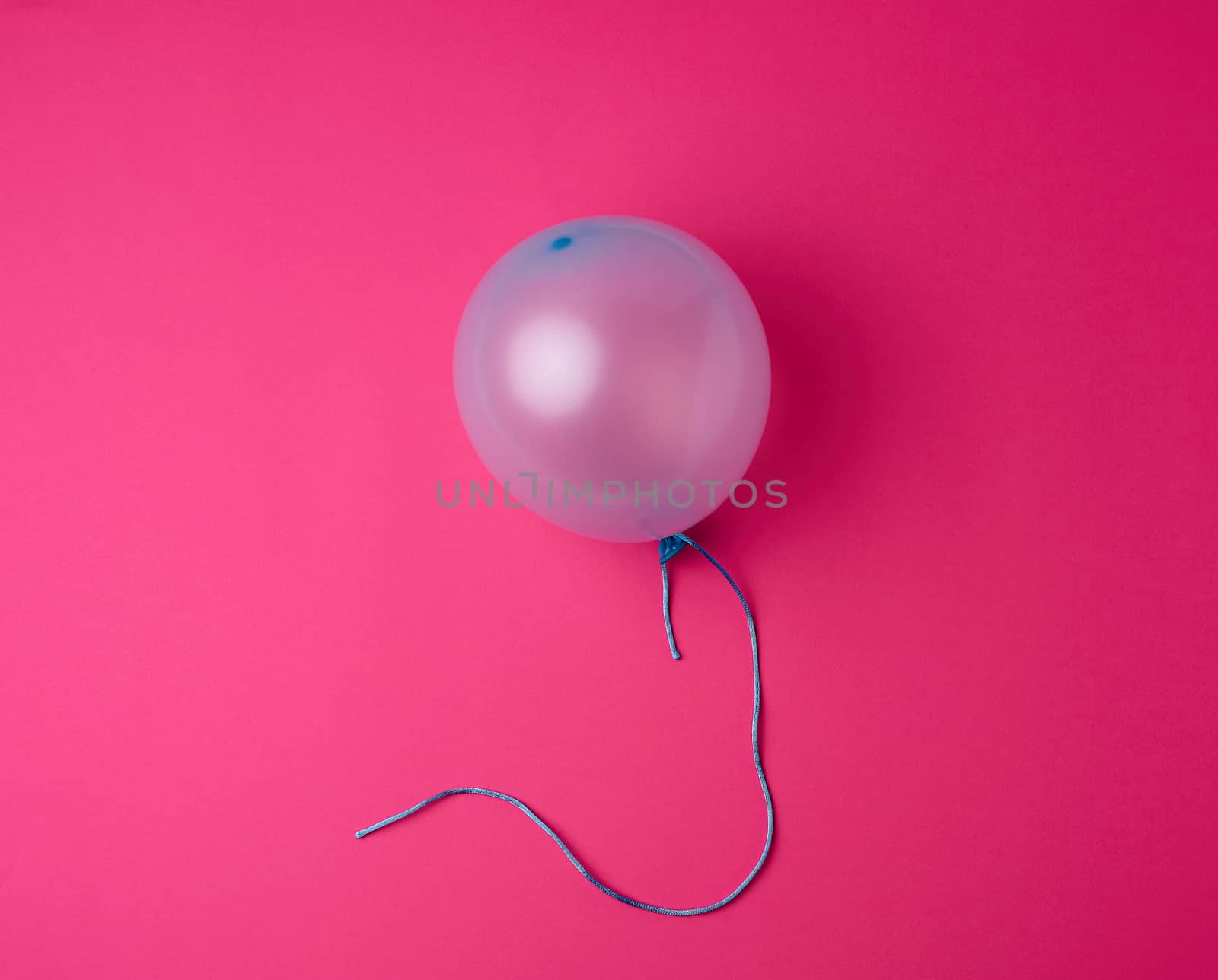 inflated blue rubber balloon on a pink background, blue rope