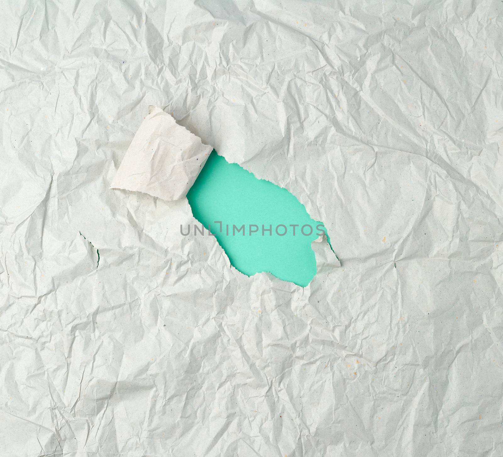 gray crumpled sheet of paper with a hole, green backing, abstract background