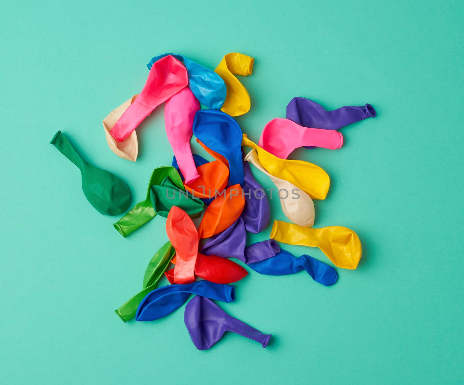 many deflated latex colorful balloons scattered on a green background, festive backdrop