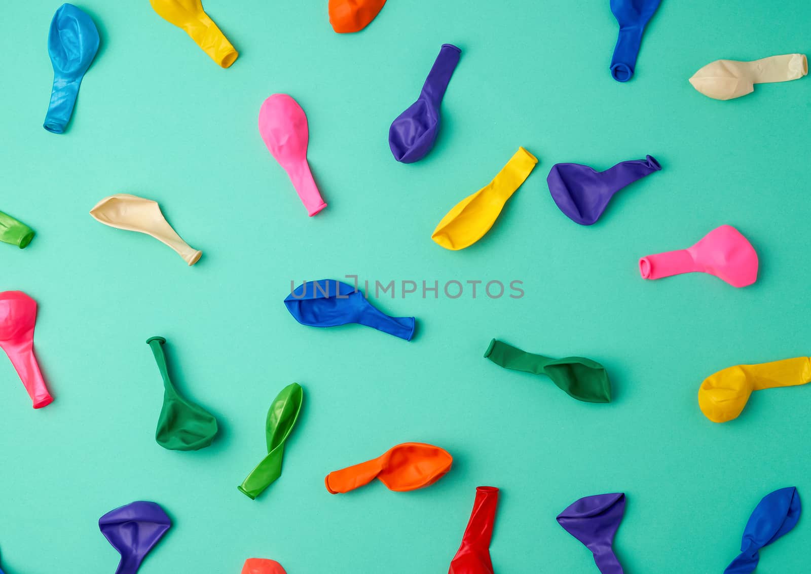 many deflated latex colorful balloons scattered on a green background, festive backdrop